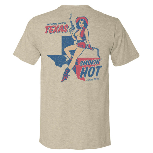 Tan tee with a graphic of a woman in a cowgirl outfit sitting on the state of Texas with text 'THE GREAT STATE OF TEXAS - SMOKIN HOT'.